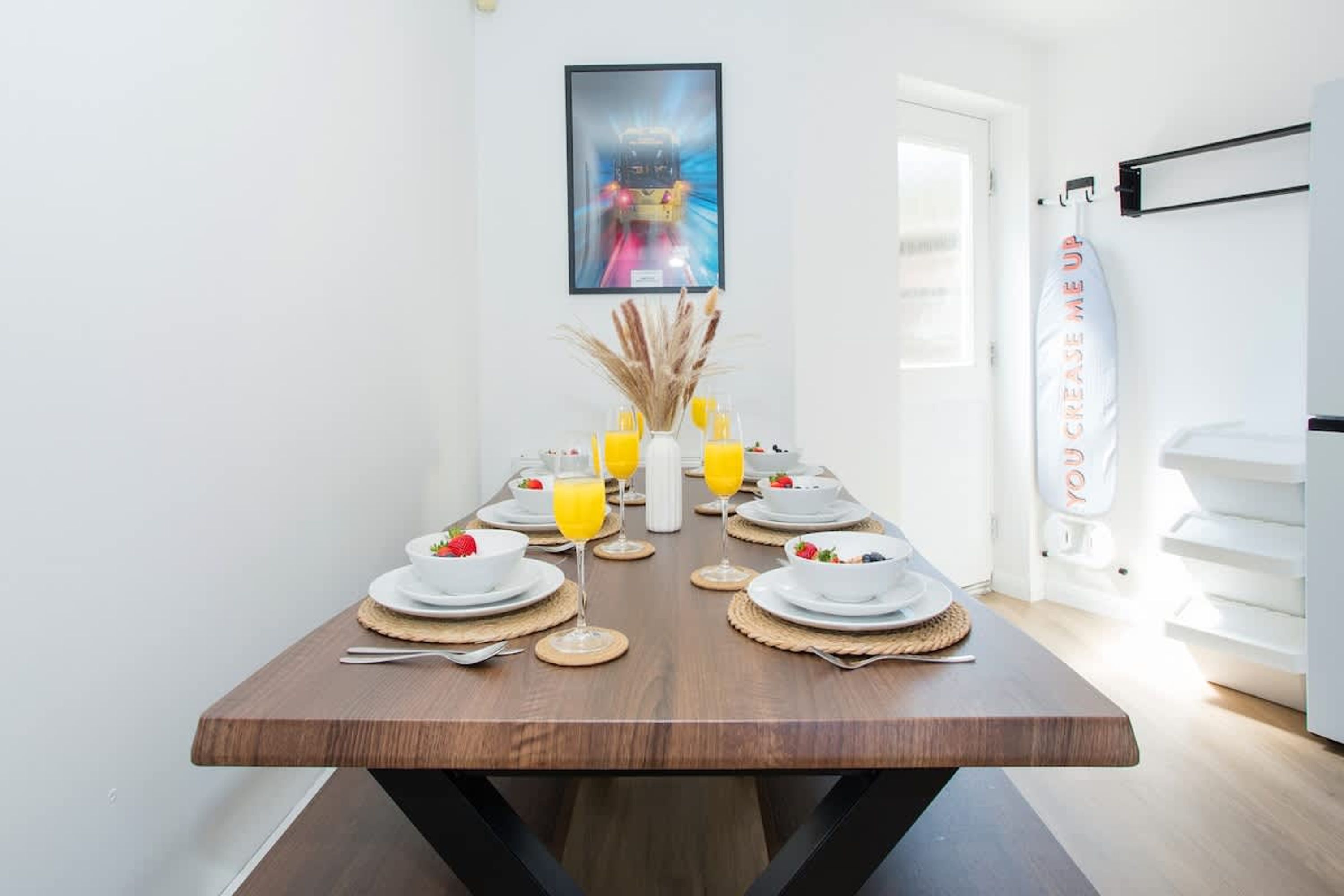 A dining table set with plates, glasses, and a vase with dried plants.