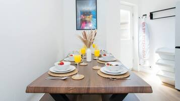 A dining table set with plates, glasses, and a vase with dried plants.