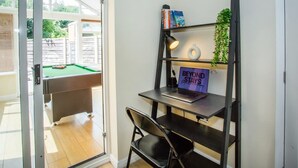 A room with a pool table, a desk with a laptop, a chair, and a bookshelf with books and a sign. - Comfy 3-bed City Home Parking Near Deansgate (Manchester)