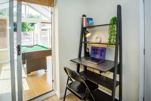 A room with a pool table, a desk with a laptop, a chair, and a bookshelf with books and a sign. - Comfy 3-bed City Home Parking Near Deansgate (Manchester)