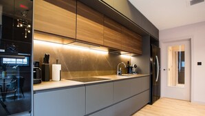 A modern kitchen with a central island, built-in appliances, and a view into the adjacent dining area. - Stylish Manchester City Escape Walk to Chinatown (Manchester)