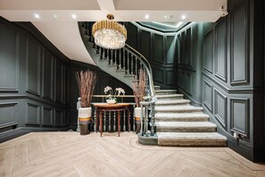 A grand staircase with a chandelier, a wooden floor, and a table with flowers. - Spacious Central Location For Families Walk to All (Manchester)