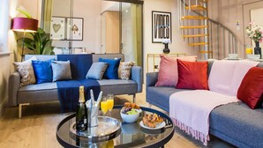 A spacious living area with a modern staircase, a round coffee table with breakfast items, and a sofa with colorful cushions. - Spacious 3-bed Retreat Modern Super Central (Manchester)