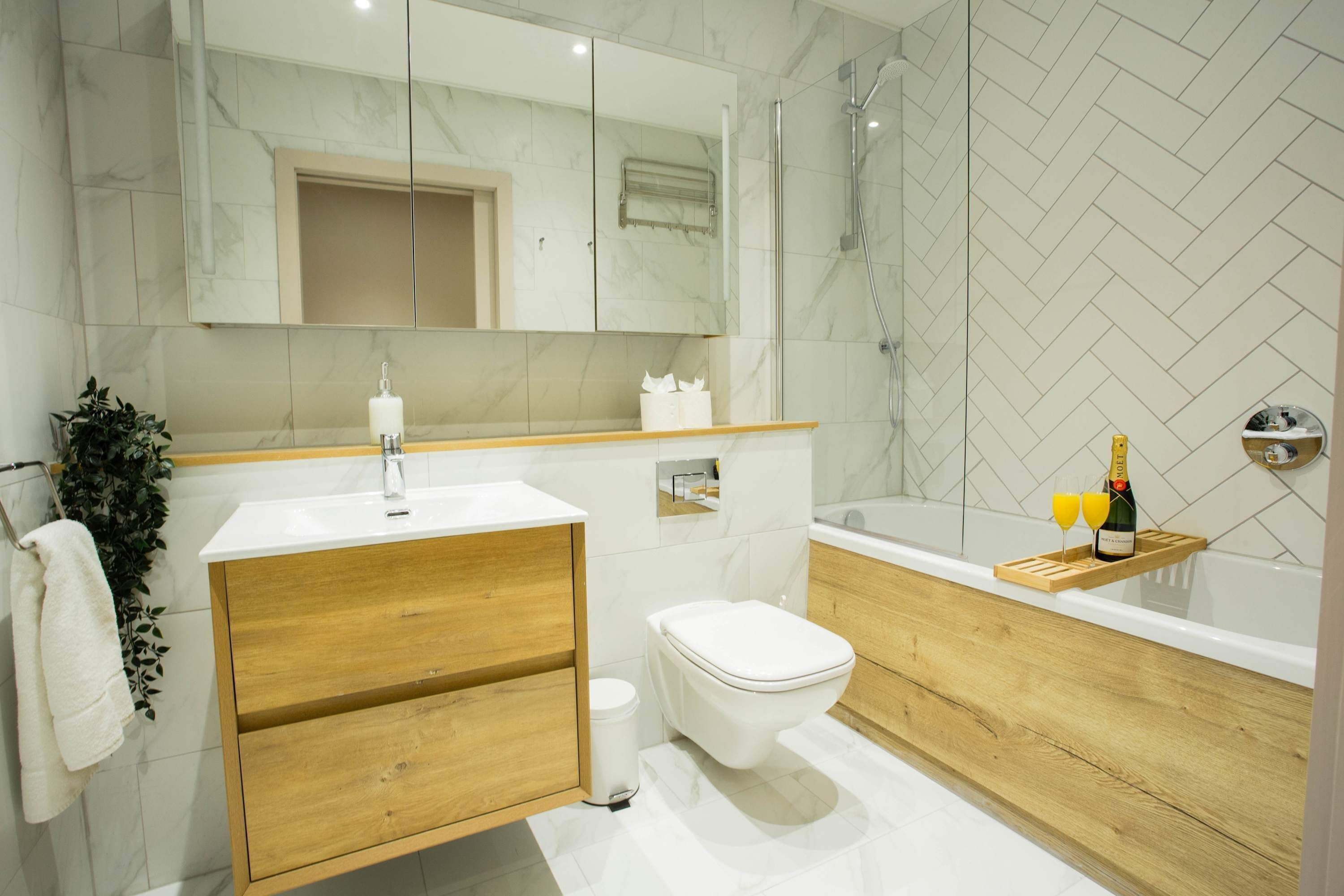 A modern bathroom with a wooden vanity, a toilet, a bathtub, and a shower.
