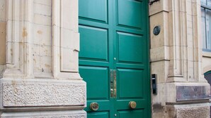 A green door with a brass knocker, flanked by stone columns, and a plaque reading '10 Charlotte House'. - Spacious 3-bed Retreat Modern Super Central (Manchester)