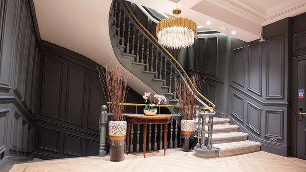 A grand staircase with a chandelier, a round table with flowers, and tall vases. - Spacious 3-bed Retreat Modern Super Central (Manchester)