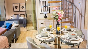 A modern hotel room with a bed, a sofa, a dining table set for breakfast, and a staircase. - Spacious 3-bed Retreat Modern Super Central (Manchester)