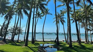 A beach with palm trees and boats in the water. - Nirvana Beach Villages (Mui Ne)