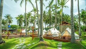 A tropical resort with palm trees, stone pathways, and multiple white tents. - Nirvana Beach Villages (Mui Ne)