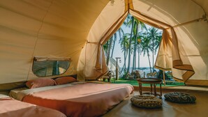 A tent with a bed, a table, and a view of palm trees. - Nirvana Beach Villages (Mui Ne)