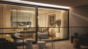 Un salon moderne avec une cloison en verre, un coin repas et une cuisine visible à travers les stores.