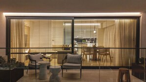 Un salon moderne avec une cloison en verre, deux fauteuils, une petite table et un canapé.
