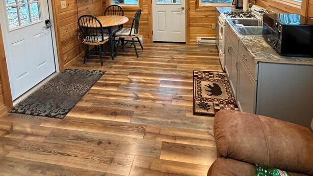 Een houten cabin met een eethoek, keuken en woonruimte, voorzien van een televisie en een open haard.