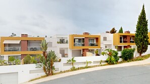 A row of modern multi-story residential buildings with balconies, a white wall with plants, and a clear sky. - 2 bedroom apartment, Vitismar, Vale Parra (Albufeira)