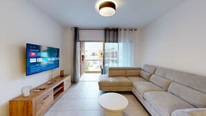 Ein modernes Wohnzimmer mit Flachbildfernseher, einer Couch, einem Couchtisch und einer Holz-TV-Bank.