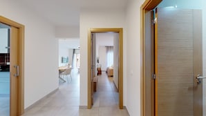Ein Flur, der zu einem Schlafzimmer mit Bett, Schreibtisch und Stuhl führt.