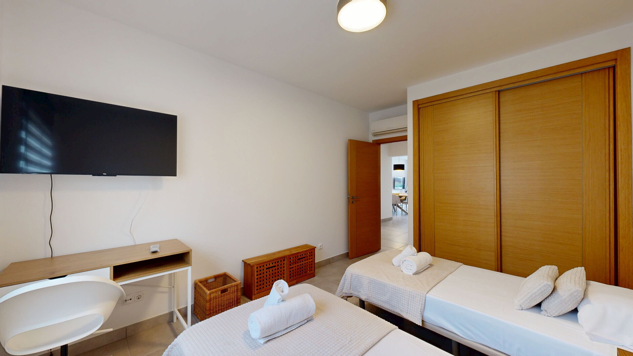 A room with two beds, a desk, a television, and a wardrobe.