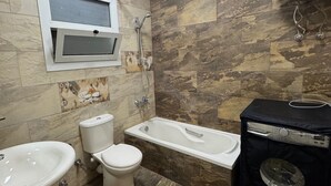 Kylpyhuone, jossa on wc, bidee, pesuallas ja kylpyamme.