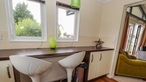 Une cuisine moderne avec deux tabourets de bar blancs, un vase vert et une décoration en forme d’étoile sur le comptoir.