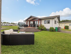 A modern house with a patio, outdoor seating, and a view of the surrounding area. - Honeysuckle Lodge (Abergele)