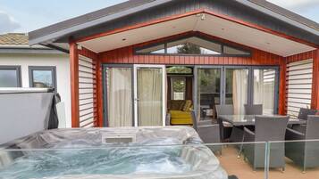 Un espace moderne pour jacuzzi extérieur, doté d’un patio couvert, de portes-fenêtres coulissantes et de mobilier d’extérieur.