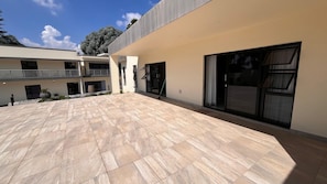 A modern building with a flat roof, large windows, and a paved courtyard.