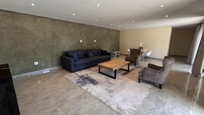 A modern living room with a sofa, armchair, coffee table, and a rug.