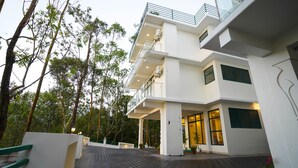 Un bâtiment moderne à plusieurs étages, doté d’une entrée abritée, d’un espace extérieur aménagé pour s’asseoir et d’un jardin.