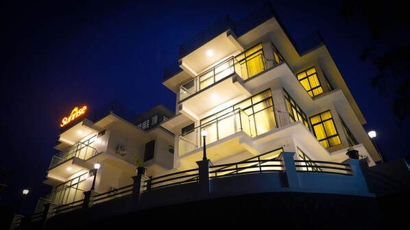 A multi-story hotel with balconies, a visible sign, and a well-lit facade.