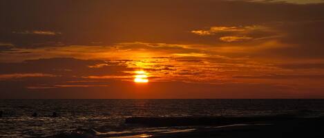 Um pôr do sol sobre o oceano com nuvens no céu.
