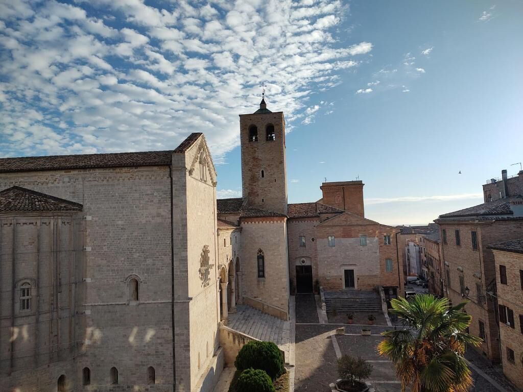 Un edificio histórico con una torre destacada, un patio con palmeras y un cielo despejado.