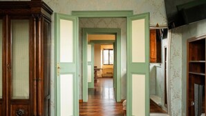 A hallway with wooden flooring, green doors, and a mirrored wall. - PALAZZO FIORENZI - DIMORA STORICA (Osimo)