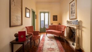 A living room with a fireplace, a sofa, a coffee table, and a door leading to a balcony. - PALAZZO FIORENZI - DIMORA STORICA (Osimo)