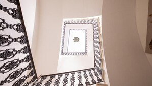 A staircase with ornate black metal railings and a patterned wall. - PALAZZO FIORENZI - DIMORA STORICA (Osimo)