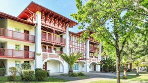 Ein Mehrstöckiges Hotel mit Balkonen, einem Innenhof und tropischer Bepflanzung.