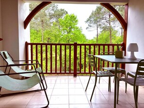 A balcony with a view of trees, a table with chairs, and a lamp. - Apartment with golf view - 4 guests (Biscarrosse)
