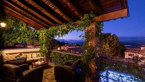 An outdoor seating area with a view of the mountains, a brick pillar, and a wooden ceiling.