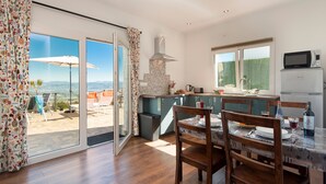 A modern kitchen with a view, a dining area with wooden chairs, and a patio with a table and chairs.
