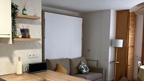 Een knus woongedeelte met een kitchenette, een bank, een lamp en een radiator.