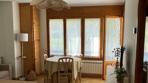 Een eetgedeelte met een tafel voor vier personen, een radiator en een raam met gordijnen.