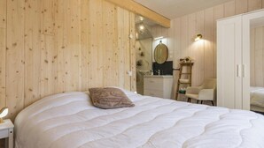 Ein Schlafzimmer mit einem großen Bett, einem Nachttisch, einem Spiegel, einem Kleiderschrank und einem Sessel.