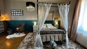 A four-poster canopy bed with white curtains, a chandelier, a framed picture collection, and a wicker chair. - Urban house, air conditioning, pets welcome – 6 guests (Moulins)