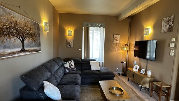 A modern living room with a sectional sofa, a coffee table, a TV, and artwork on the walls. - Urban house, air conditioning, pets welcome – 6 guests (Moulins)