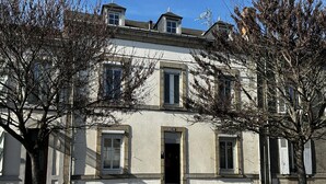A two-story building with a symmetrical facade, a central entrance, and a visible window number '70'. - Urban house, air conditioning, pets welcome – 6 guests (Moulins)