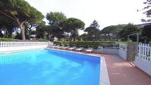 A swimming pool with lounge chairs and a white fence. - Spacious Apartment With two Balconies (Lignano Sabbiadoro)