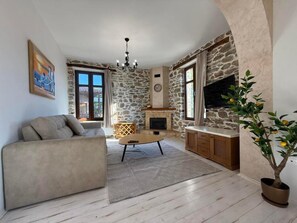 Una sala de estar con chimenea de piedra, un sofá, una mesa de centro y un televisor.