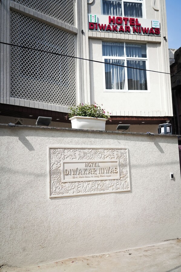 Placa de hotel com o nome 'HOTEL DIWAKAR NIWAS' e uma placa abaixo.