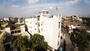A multi-story hotel with a rooftop flag, surrounded by other buildings and trees. - HOTEL DIWAKAR NIWAS (Jaipur)