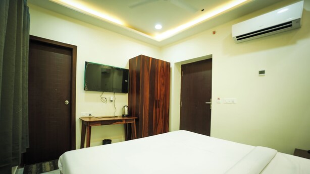 A hotel room with a bed, a desk, a mirror, an air conditioner, and a door. - HOTEL DIWAKAR NIWAS (Jaipur)