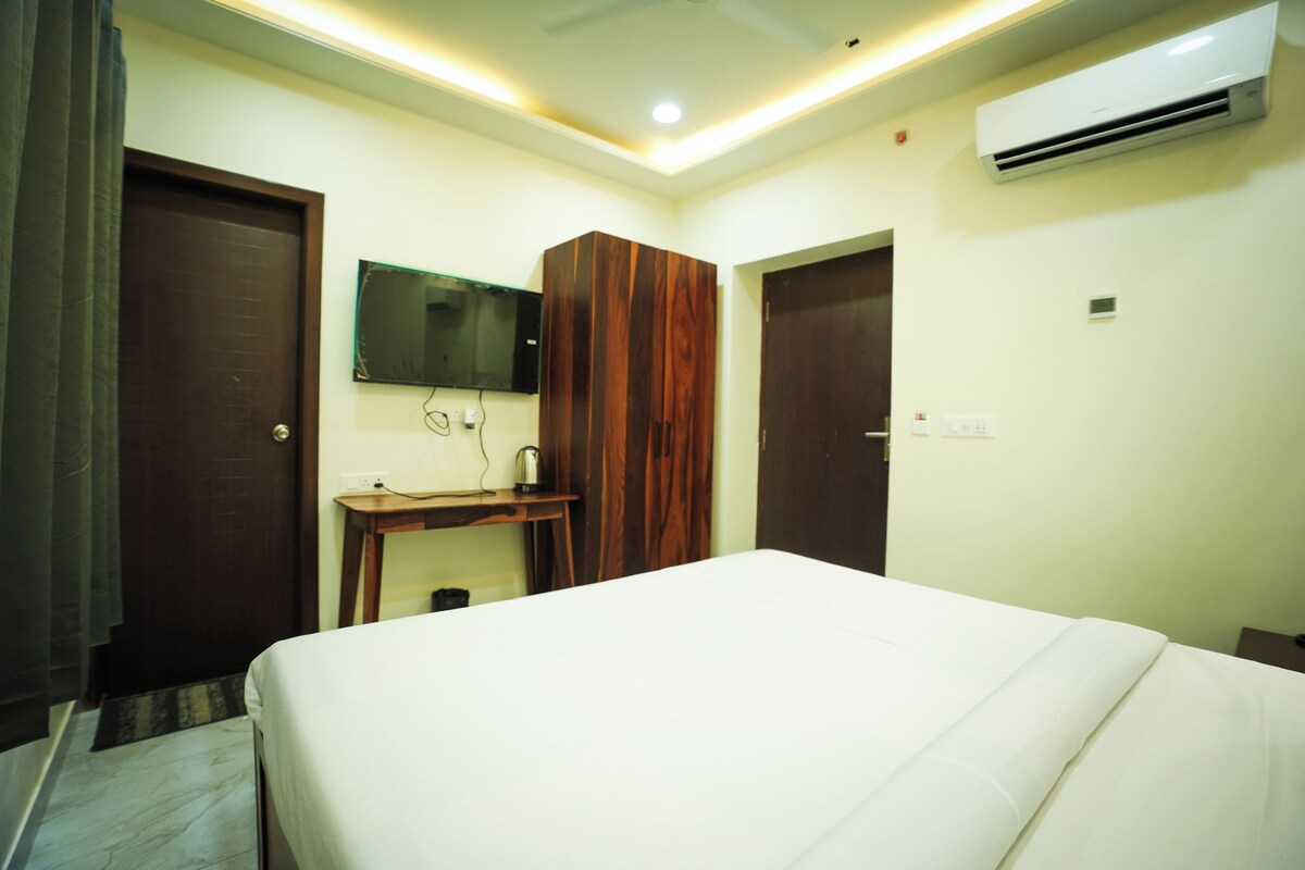 Quarto de hotel com uma cama, escrivaninha, espelho, ar condicionado e porta.